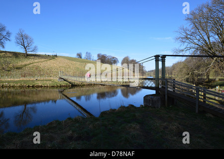 Frau, die über die Hängebrücke über den Fluss Wharfe in der Nähe von Hebden auf die Dales Weg lange Strecke Fußweg Yorkshire Stockfoto