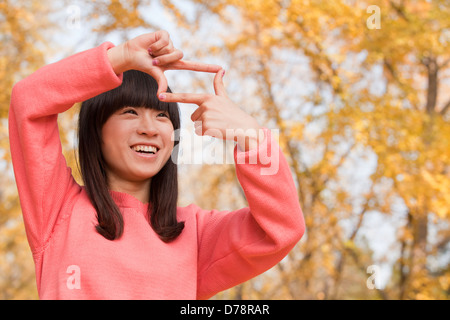 Junge Frau mit Fingern einrahmen Stockfoto