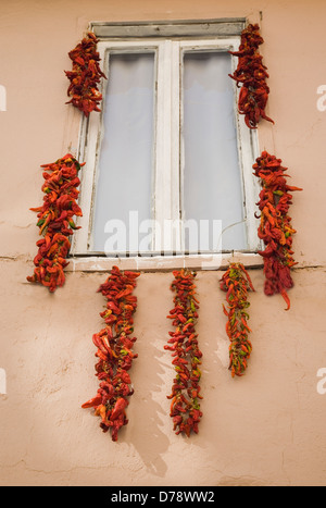 Türkei Aydin Provinz Kusadasi Saiten rot orange Paprika zum Trocknen im Sommersonne von Fensterrahmen des Hauses aufgehängt Stockfoto