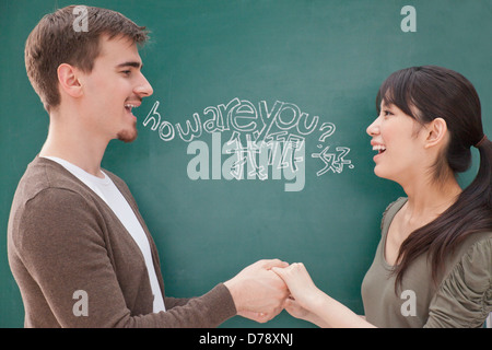 Porträt des Lächelns männliche Lehrer und Schüler vor der Tafel, die Hand in Hand Stockfoto