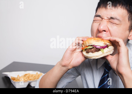 Junger Geschäftsmann einen Burger genießen Stockfoto