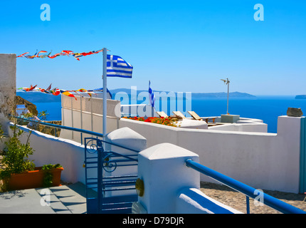 Schöne weiße Terrasse im Resort auf der Insel Santorin in Oia, Griechenland. Traditionelle griechische Architektur und Nationalflagge Stockfoto