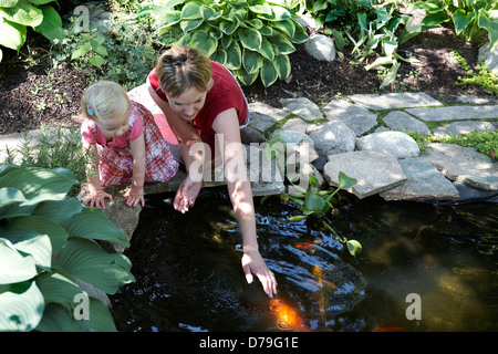 Mutter und Tochter, die Koi Fische füttern Stockfoto