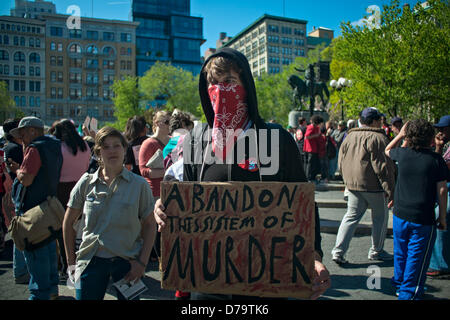 Mittwoch, 1. Mai 2013, New York, NY, Vereinigte Staaten: A maskierten Mann hält ein Schild mit der Aufschrift "dieses System des Mordes' verlassen wie Demonstranten am New Yorker Union Square zum International Workers Tag, auch bekannt als Maifeiertag sammeln. Stockfoto