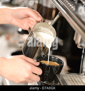 Kellnerin Hände Gießen Milch Cappuccino machen Stockfoto