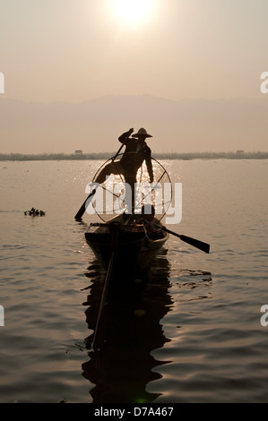 Intha Fischer und seine konische Net Silhouette in seinem Boot am Inle See Myanmar (Burma) Stockfoto