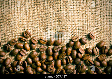 die Kaffeebohnen auf Sackleinen Hintergrund Stockfoto