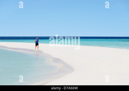 Mann läuft am schönen Strand Stockfoto