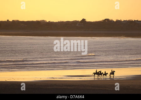 Menschen Reiten in den Sonnenuntergang am Strand von Ogmore-by-Sea. Stockfoto