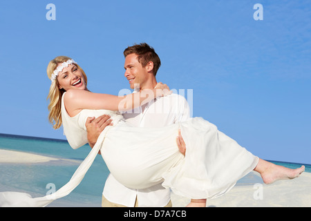 Bräutigam trägt Braut am schönen Strandhochzeit Stockfoto