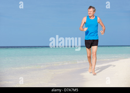 Ältere Mann läuft am schönen Strand Stockfoto