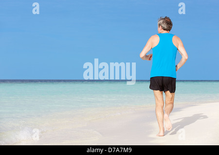 Ältere Mann läuft am schönen Strand Stockfoto