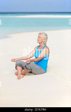 Ältere Frau meditieren am Strand Stockfoto