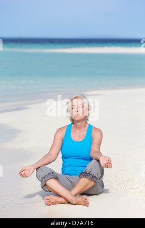 Ältere Frau meditieren am Strand Stockfoto