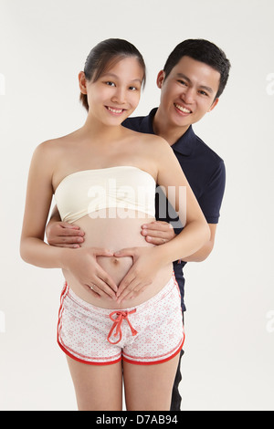 Lächelnder Mann umarmt seine schwangere Frau Stockfoto