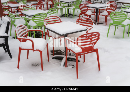 Stühle und Tische, die zu Beginn des Frühlings mit Schnee bedeckt Stockfoto