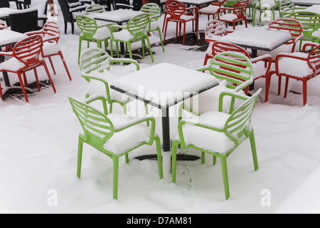 Stühle und Tische, die zu Beginn des Frühlings mit Schnee bedeckt Stockfoto