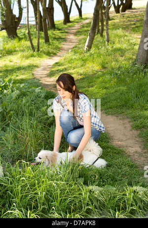 Frau und ihr kleines Spielzeug Rasse Hündchen spazieren entlang einer ländlichen Spur durch den Wald in der Sommersonne Stockfoto