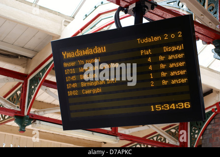 Eisenbahn Zug mal auf einer beleuchteten Brettvertretung Zug mal in der walisischen Sprache in Wrexham Allgemeine Station Stockfoto