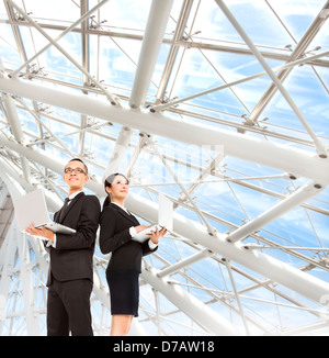 junger Geschäftsmann und Frau Holding Laptop und Stand im modernen Büro Stockfoto