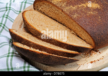 Runde Vollkorn Brot (Boule oder Cob) bestäubt mit Grieß auf ein Schneidbrett aus Holz. Stockfoto