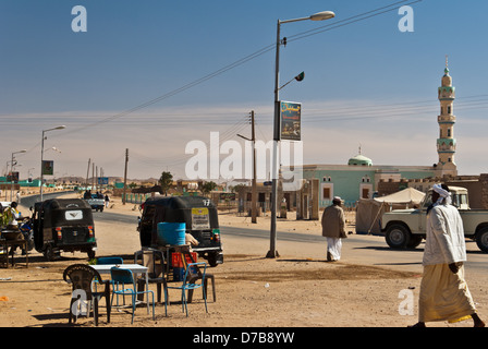 Straße in Wadi Halfa, Männer in Galabijas, einige Auto-Rikschas (Tuk-Tuk) sind sichtbar und Moschee mit Minarett in bg, Nord-Sudan Stockfoto