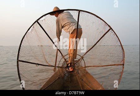 Intha Bein Rudern Fischer gesehen durch seine kegelförmige Netz am Inle See Myanmar (Burma) Stockfoto