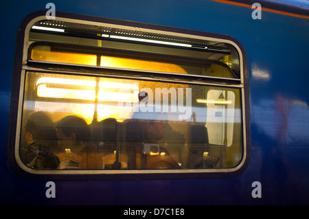 Passagiere auf Zug wie durch Fenster gesehen Stockfoto