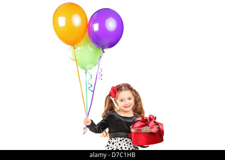 Ein lächelndes Mädchen hält ein Geschenk und Haufen Luftballons isoliert auf weißem Hintergrund Stockfoto