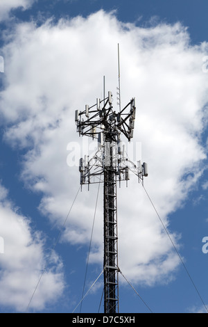 Eine Mobilfunkantenne Turm über einem blauen Himmel mit weißen flauschigen Wolken isoliert. Stockfoto