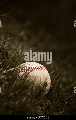 Ein Alter und abgenutzte Grunge Baseball sitzen in dem grünen Rasen in Sepia-Farbton. Stockfoto