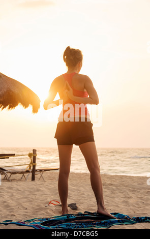 Mexiko, Playa del Carmen, junge Frau Yoga am Strand bei Sonnenaufgang Stockfoto