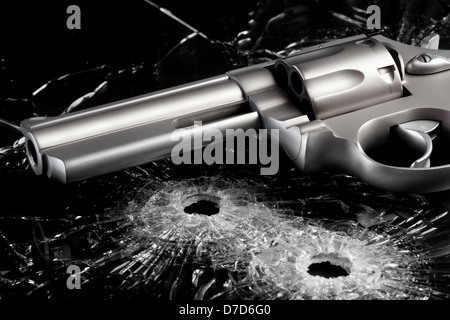 Pistole mit zwei Einschusslöcher in Glas über schwarz - moderne Revolver hautnah Stockfoto