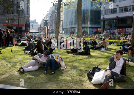 Leicester Square, London England Menschen entspannen auf dem Rasen Stockfoto