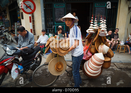 Ein Mann verkaufte Reis Hüte und Körbe von seinem Fahrrad in der Altstadt, Hanoi. Stockfoto