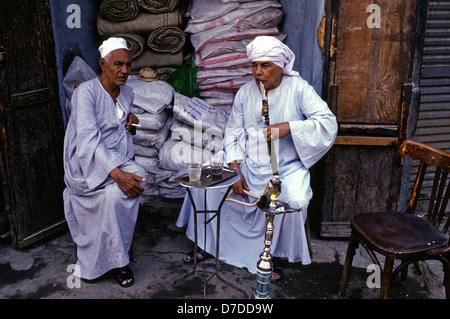 Ägypter, die traditionelle Galabyeh Kleidungsstück und Rauchen Shisha Pfeife im Khan el-Khalili einen großen Souk in der Altstadt von Islamischen Kairo Ägypten Stockfoto