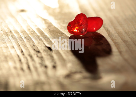Zwei rote Glas-Herzen auf Schreibtisch aus Holz Stockfoto