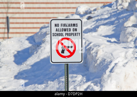 Keine Schusswaffen erlaubt auf Schule Eigenschaft Schild außerhalb einer Schule im Schnee. Stockfoto