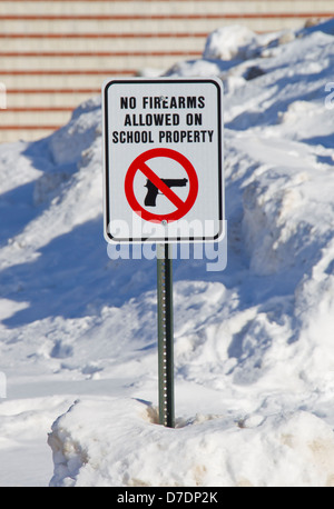 Vollständige Ansicht des No Schusswaffen zulässig auf Schule Eigenschaft Schild außerhalb einer Schule im Schnee. Stockfoto