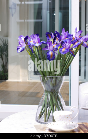 Schöne künstliche Iris Blumen in einer Glasvase Stockfoto