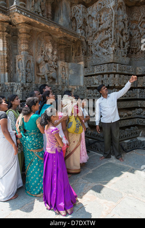 Eine Anleitung zeigt eine Gruppe von indischen Touristen Details der hinduistischen Hoysaleswara Tempel in Dorasamudra, in der Nähe von Hassan, Karnataka, Indien Stockfoto