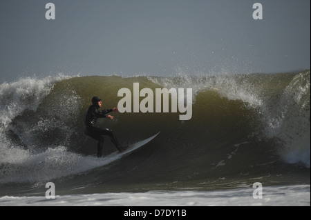 Eine Curling-Welle droht, eine Surfer zu verschlingen, als er über das Gesicht Geschwindigkeiten.  Surfen auf Gower, Wales, UK Stockfoto