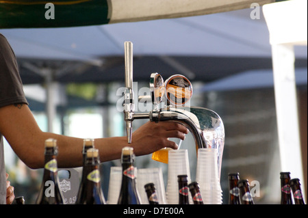 Ein Barkeeper Gießen real Ale aus Bier Hähne aus Greenwich Zwischenzeit Brauerei Stand, South Bank, London, England Stockfoto