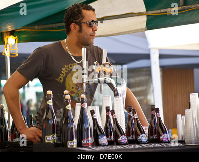 Ein Barkeeper Gießen real Ale aus Bier Hähne aus Greenwich Zwischenzeit Brauerei Stand, South Bank, London, England Stockfoto