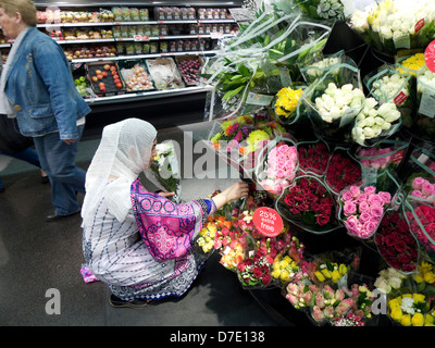 Eine muslimische Frau in farbenfrohem Kleid, die schöne Schnittblumen kauft Im M&S Inside Marks & Spencers Store in Cardiff City Centre Wales Großbritannien KATHY DEWITT Stockfoto