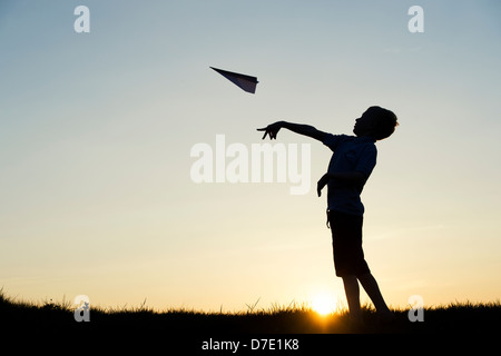 Junge werfen ein Papier Flugzeug bei Sonnenuntergang. Silhouette Stockfoto