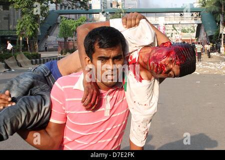 Dhaka, Bangladesch. 5. Mai 2013. Zivile Personen tragen einen verletzten islamistischen Demonstranten bei Zusammenstößen mit der Polizei in Dhaka am 5. Mai 2013.Thousands der Islamisten Dhaka am 05 Mai zum Stillstand gebracht, wie sie eine Anti-Blasphemie-Gesetz gefordert, die die Todesstrafe steht, und Beamte sagten, dass ein Arbeiter bei Zusammenstößen zwischen Demonstranten und der Polizei getötet wurde. Unterstützer der radikalen Hefazat-e-Islam-Gruppe durchgeführt Stöcke und blockiert wichtige Einstiegspunkte in die Stadt Stockfoto