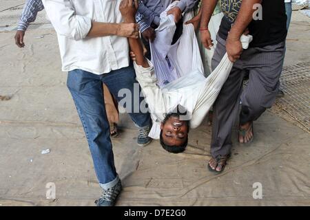 Dhaka, Bangladesch. 5. Mai 2013. Zivile Personen tragen einen verletzten islamistischen Demonstranten bei Zusammenstößen mit der Polizei in Dhaka am 5. Mai 2013.Thousands der Islamisten Dhaka am 05 Mai zum Stillstand gebracht, wie sie eine Anti-Blasphemie-Gesetz gefordert, die die Todesstrafe steht, und Beamte sagten, dass ein Arbeiter bei Zusammenstößen zwischen Demonstranten und der Polizei getötet wurde. Unterstützer der radikalen Hefazat-e-Islam-Gruppe durchgeführt Stöcke und blockiert wichtige Einstiegspunkte in die Stadt Stockfoto