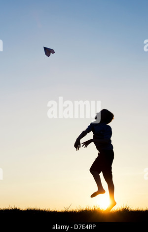 Junge werfen ein Papier Flugzeug bei Sonnenuntergang. Silhouette Stockfoto