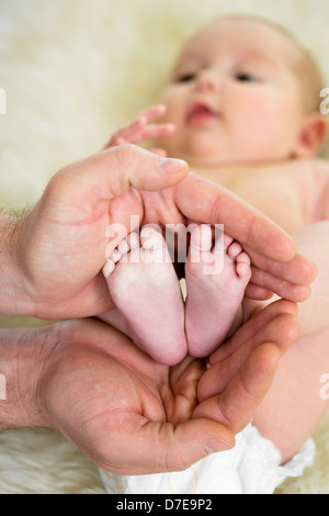 Vaters Hände halten kleine Babys Füße Stockfoto